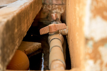 Close-up Vintage Old PVC Pipe with Red Valve on Dirty Concrete Wall - Water Supply