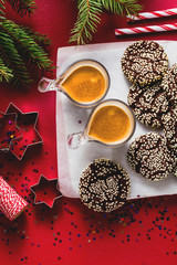 Christmas chocolate cookies with sesame and New Year's festive decorations on the table and two cups of espresso coffee