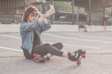 Stylish beautiful young woman in glasses and denim jacket rollerblading, dancing and having fun....