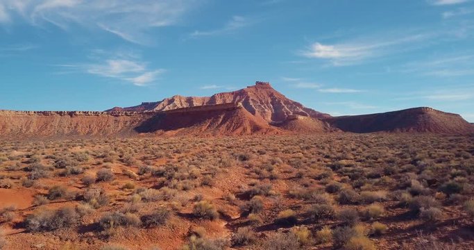 4K flying fast over the desert toward a red rock mesa revealing a mountain in the distance.