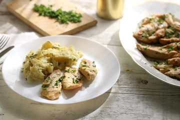 Grilled chicken with fresh parsley and mashed potatoes on a rustic white table. Selective focus.
