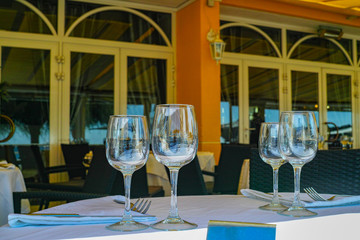 Elegant restaurant on French Riviera is waiting for guests, served dinner table with glasses, tableware and white linnen napkins