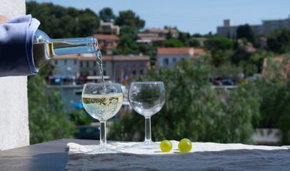 Waiter pouring white wine on outdoor cafe terrace