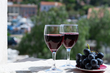 Two wine glasses with red wine served with red grape on outdoor terrace