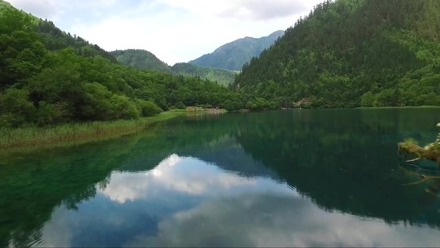 Impressive drone shot from a wooden balcony towards a beautiful blue river and luscious green mountainside