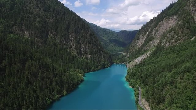 Smooth reversal drone shot over a turquoise coloured river between mountains