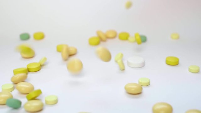 Close Up of Many Colorful Medical Pills, Tablets, Capsules and Drugs Falling to a White Background