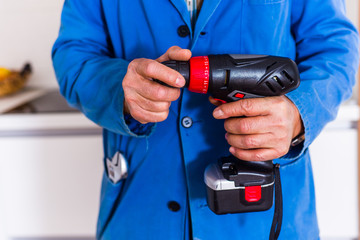 Workman holding power drill in kitchen