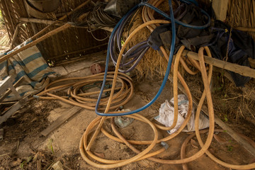 Vintage Old Hoses on Dirty Concrete Ground - Hay, Wood and Plastic Sheet in Messy Chicken Coop © Anne Spelledwithane