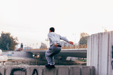 Young man practicing parkour at the city park,doing tricks and jumps.