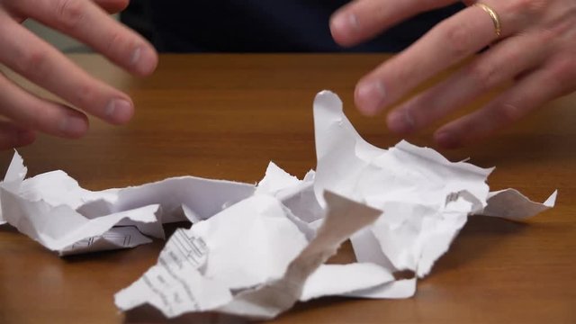 Hands are rowing away torn documents and showing fists with a cookie.
