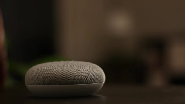Voice controlled mini speaker turns on a light in a smart home at night