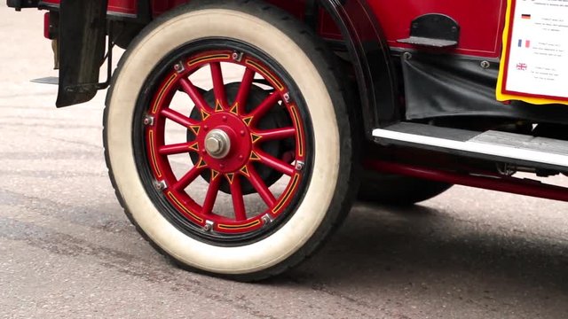Close up shot of the rear wheel of an oldtimer bus coach while reversing with exhaust fumes coming from the steam engine.