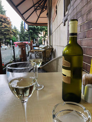 Bottle of white Georgian wine and glasses on the table. Sunny day in the cafe