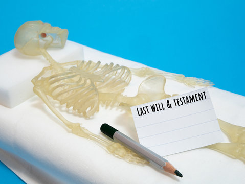last will and testament concept with human skeleton laying on deathbed with pencil and piece of paper