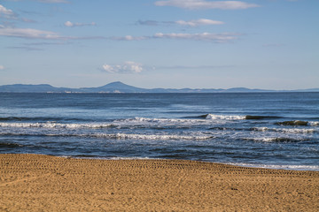 sea coast view with waves, sand beach and blue sky