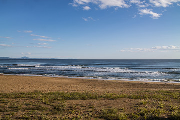 sea coast view with waves, sand beach and blue sky