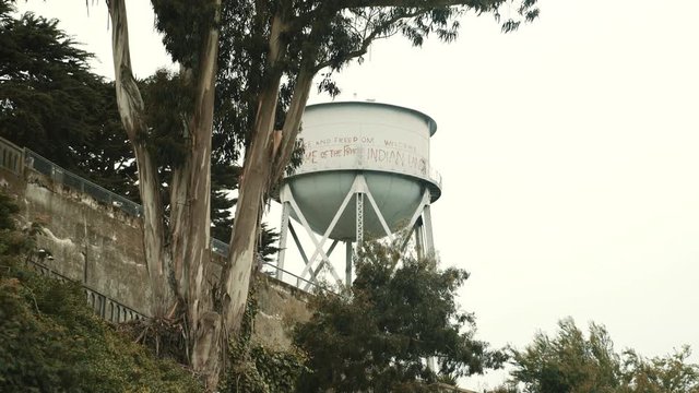Wide tilt up shot of water reservoir and tree on Alcatraz island, San Francisco, USA
