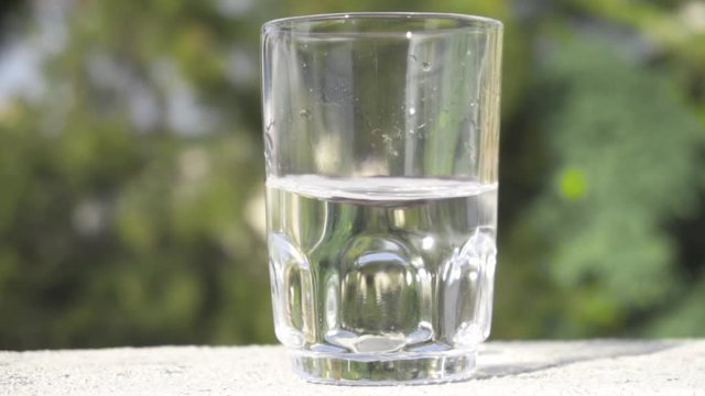 Glass half filled with water which is swirling in slow motion