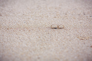Fototapeta na wymiar Two wedding gold rings in the sand on the background of beach