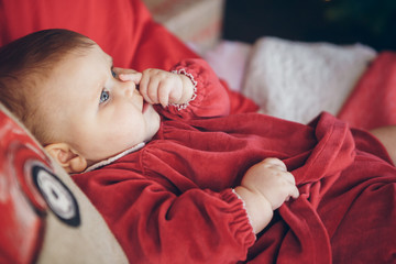 Sweet baby girl on the red bed with new year pillow. Christmas decoration