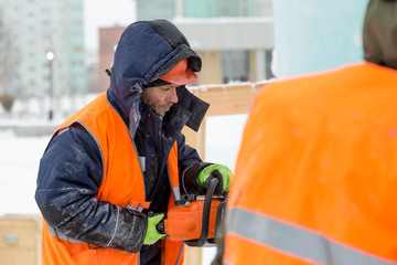 Portrait of a fitter in a vest with a chainsaw in his hands