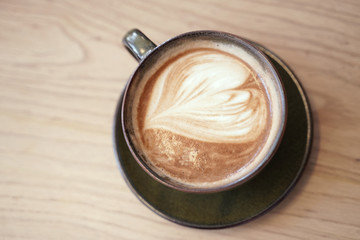Hot cafe latte with heart shape latte art in dark cup