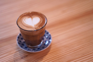 Hot cafe latte with heart shape latte art in small glass cup