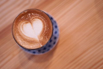 Hot cafe latte with heart shape latte art in small glass cup