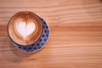 Hot cafe latte with heart shape latte art in small glass cup