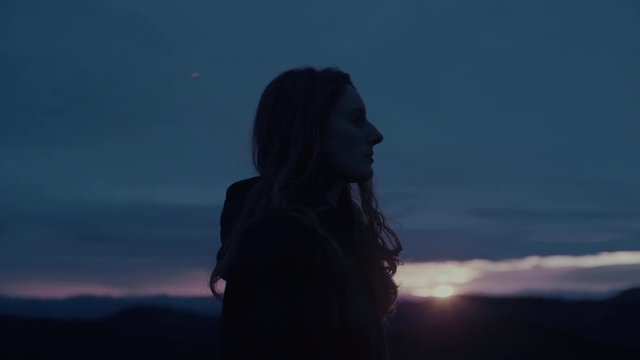 A portrait of a woman with the sun setting behind her.