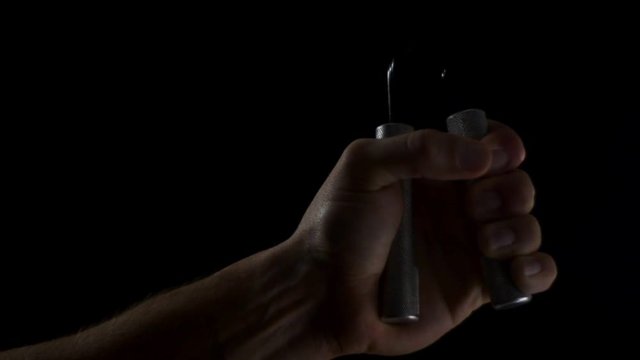 Hand squeezing exercise grips in front of a black background.