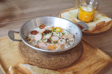 Breakfast fried eggs with sausage and toast in a small pan.