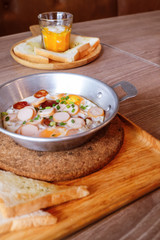 Breakfast fried eggs with sausage and toast in a small pan.