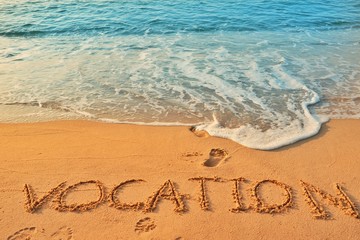 The word Vocation handwriting on sand beach with blue waves background.