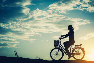Fototapeta na wymiar Silhouette of women with bicycle and beautiful sky