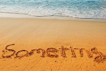 The word someting handwriting on sand beach with blue waves background.