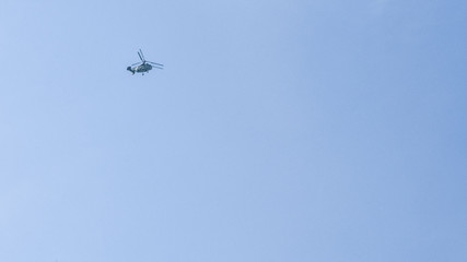 small silhouette of a helicopter on a background of clean blue sky. copy space for text