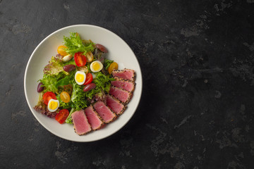 Fototapeta na wymiar Sliced Steak of tuna in sesame and a salad of fresh vegetables and quail eggs.