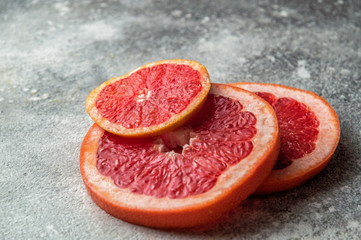 Close up. Bright red mugs of sliced grapefruit on a gray concrete background. Copy space.