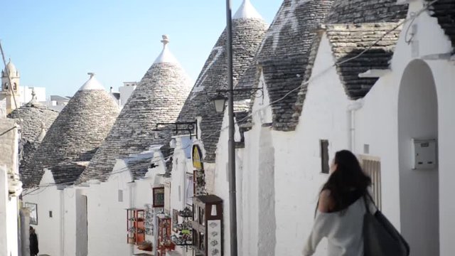 giovane donna passeggia tra i trulli di Alberobello in Puglia