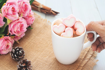 Obraz na płótnie Canvas Woman hand holding a hot chocolate with pink marshmallows on top. Love, beauty, Valentine's Day