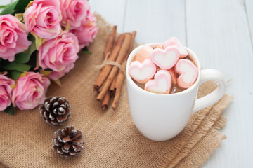 Pastel heart marshmallows on hot chocolate cup with pink roses. Love lifestyle or Valentine's Day concept