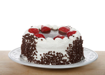 Chocolate cake frosting in vanilla cream with chocolate glaze topping surrounded by fresh cut strawberries dipped in glaze. Chocolate chip morsels pressed into the side of cake. Isolated.