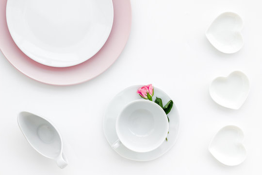 Elegant table setting with white and pink plates and floral decor on white background top view