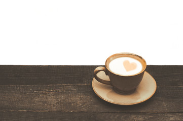 Cup of coffee with milk on a wooden table. White background. A heart