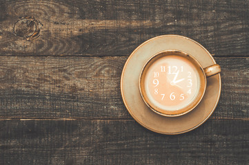A cup of coffee with milk on a dark background. Clock. Coffee break. Top view.