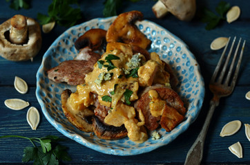 Tenderloin with mushrooms on a rustic plate on a blue wooden background