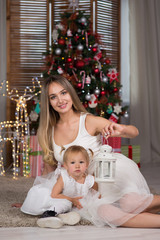 Obraz na płótnie Canvas mom and daughter are sitting around the Christmas tree