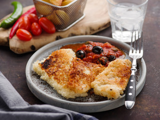 Fried fish with tomato-olive sauce and potatoes.